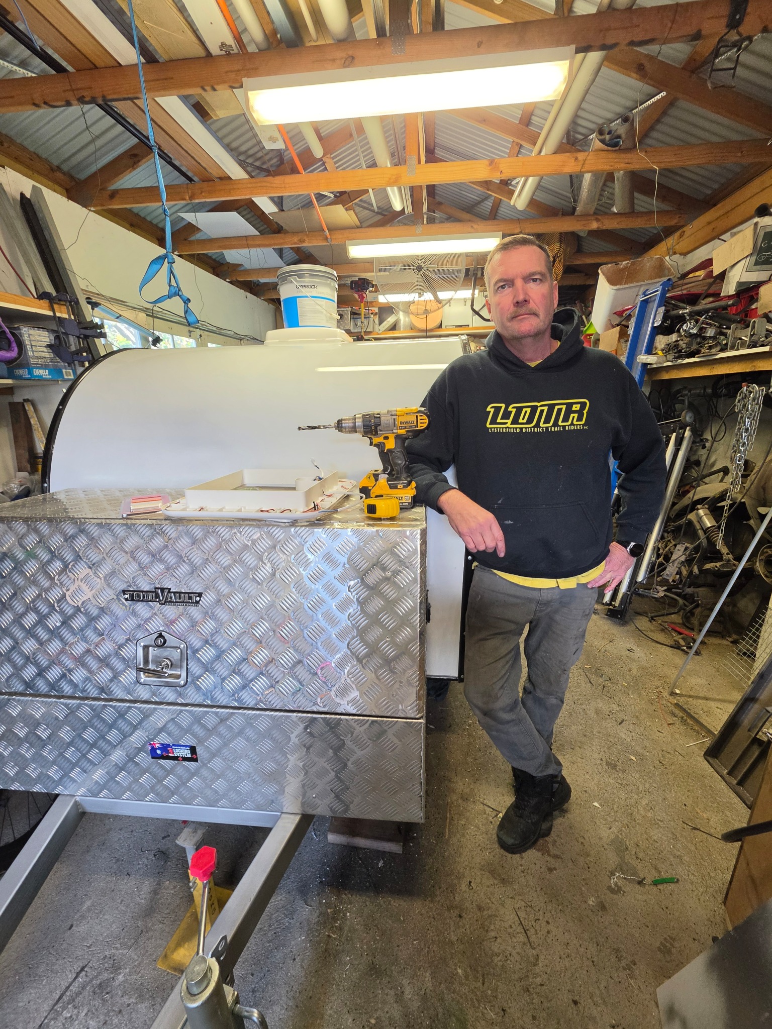Derek standing beside a green Mini Camper in his Bentleigh workshop